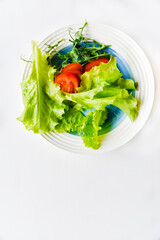 Salad on a white plate tomatoes greens and peas. White background.