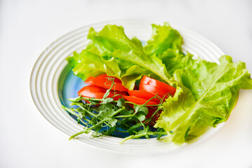 Salad on a white plate tomatoes greens and peas. White background.