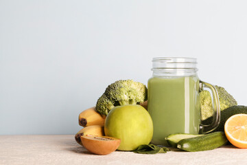 fresh green smoothie in glass bottle with vegetables on blue background.vegan food, self care and healthy lifestyle.Healthy detox diet