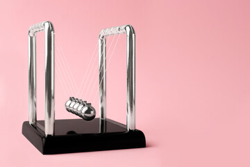 Newton's cradle on pink background, space for text. Physics law of energy conservation