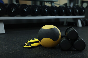 Naklejka na ściany i meble Yellow medicine ball, weighting agents and dumbbells on floor in gym, space for text
