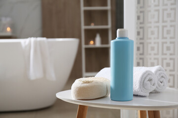 Fototapeta na wymiar Bottle of shower gel, sponge and fresh towels on white table in bathroom. Space for text