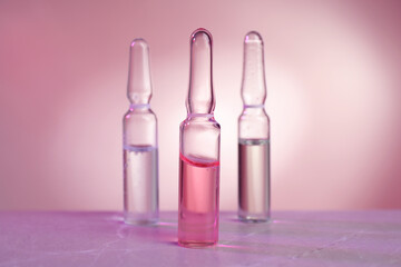 Pharmaceutical ampoules with medication on grey table against color background.