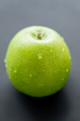 close up view of green and fresh apple with water drops on black.
