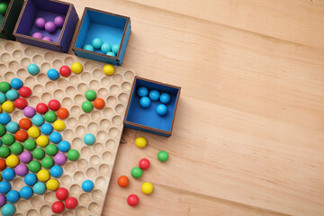Wooden sorting board and boxes with colorful balls on table, flat lay. Montessori toy