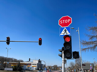 Fototapeta Traffic lights and road signs on pole against blue sky obraz