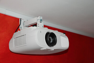 Modern digital video projector on red wall indoors, closeup - obrazy, fototapety, plakaty