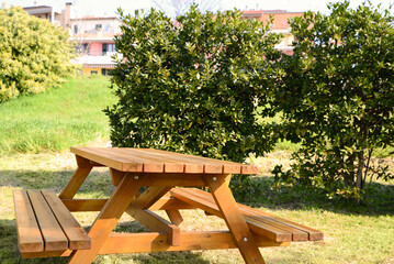 Empty wooden picnic table with benches in park on sunny day