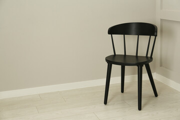Black wooden chair near light wall in room. Space for text