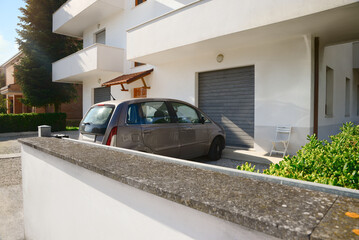 Fototapeta Modern apartment building with parked car in yard on sunny day obraz