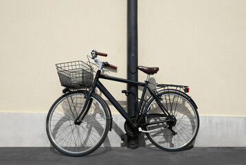 Fototapeta Vintage bicycle with basket locked to street post outdoors obraz