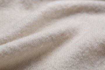 Fototapeta na wymiar Soft beige knitted fabric as background, closeup