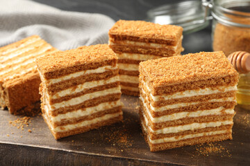 Delicious layered honey cake on wooden board, closeup
