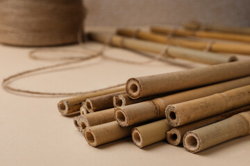 Dry bamboo sticks and twine on beige background, closeup. Space for text
