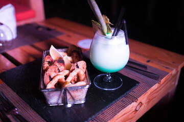 Small portion of onion rings with a cold cocktail drink beside it