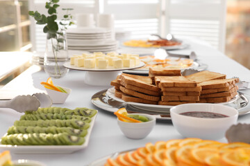 Clean dishware and different meals for breakfast on white table indoors. Buffet service