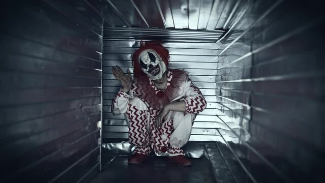 Scary clown attacks in a closed ventilation duct. Scary psychopath in a suit.