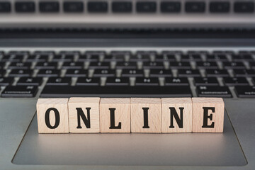 Online text on wooden block with open laptop.