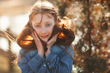 Pretty young red-haired girl outdoors. Teenager closeup portrait. Cheerful young girl outside in...