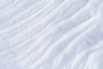 Freshly fallen snow surface looking like dunes shaped by wind. Winter abstract snow texture background.