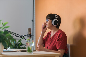 Middle-aged female radio presenter talking into the microphone and reading news - radio broadcast...
