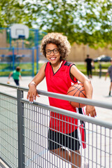 girl with afro hairstyle with a ball on a basketball court