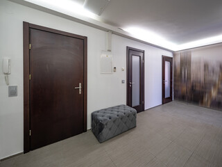 Interior of entrance hall in modern apartment. Grey floor. Closed doors.
