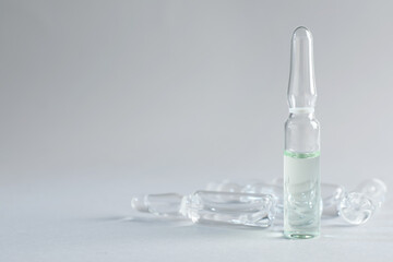 Pharmaceutical ampoules with medication on light grey background. Space for text - obrazy, fototapety, plakaty