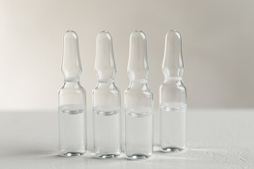 Pharmaceutical ampoules with medication on white table against light background