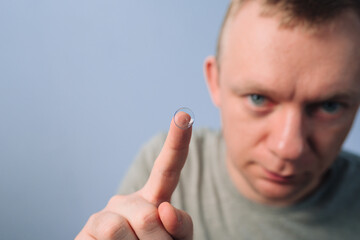 Man shows on the contact lens on finger. Contact lenses for vision improvement. Health care and medicine concept