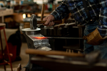 Blacksmith Working with a Hammer to Flatten an Iron Rod