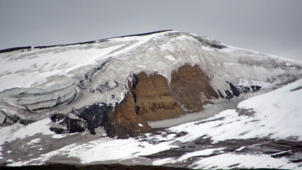 Fototapeta na wymiar Snow covered mountain peak in a desolate landscape on Deception Island, South Shetland Islands, Antarctica