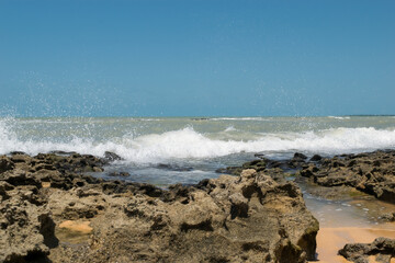Fototapeta na wymiar Linda praia com muitas pedras sendo banhadas pelas ondas, localizada em Cabrália na região de Porto Seguro, Bahia, Brasil.