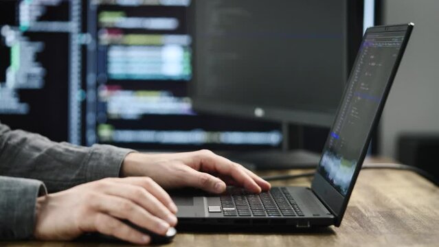 Unrecognizable programmer developer, writes code. Modern workplace with powerful PCs and monitors