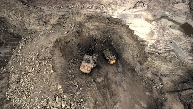 Mining excavator loading dolomite minerals in haul truck. Limestone mining in a dolomite quarry. Extraction of crushed stone in an open pit. Mining truck transports limestone from opecast, drone view.