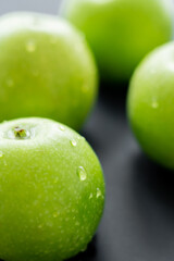 close up view of fresh apples with water drops on black.