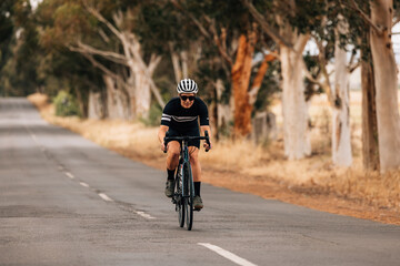 Obraz na płótnie Canvas Professional cyclist in sportswear practicing on a long countryside road