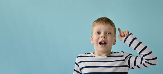 An attractive Caucasian 9-year-old boy raises his index finger up, he came up with a brilliant idea.