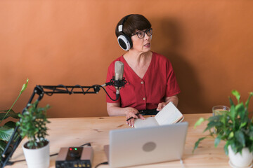 Middle-aged female radio presenter talking into the microphone and reading news - radio broadcast...
