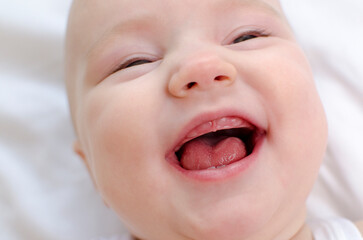 Baby smiling with a toothless mouth close-up. Infant laughing. Children healthcare