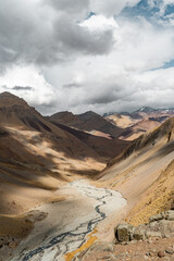 Vertical shot of a colorful mountain valley with a river on a sunny day with clouds, Chile
