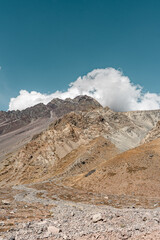 Vertical shot of clouds creating shadow over colorful mountains in Cajon del Maipo, Chile