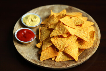 Corn chips nachos with sauces on a wooden board. Mexican snack.