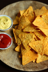 Corn chips nachos with sauces on a wooden board. Mexican snack.