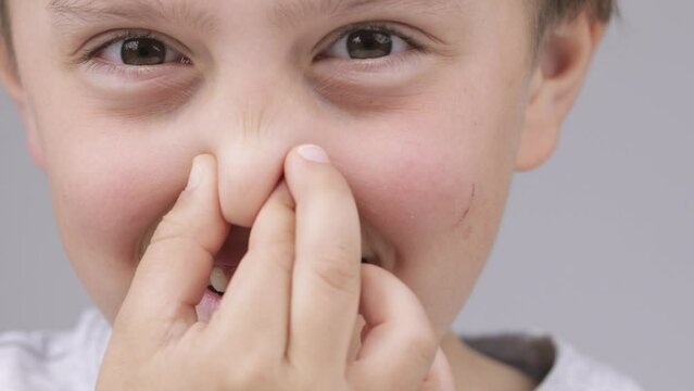 Caucasian boy of 9 years expresses unsatisfaction with a smell in the room.