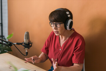 Middle-aged female radio presenter talking into the microphone and reading news - radio broadcast...