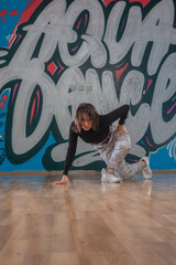 Attractive young woman doing breakdance move over graffiti background