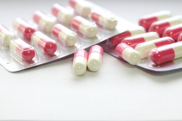 Pink-green pill capsules were placed on a white table.