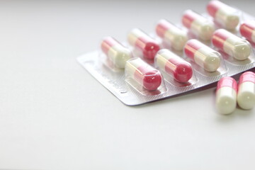 Pink-green pill capsules were placed on a white table.