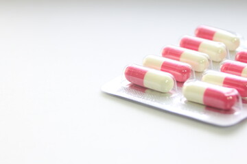 Pink-green pill capsules were placed on a white table.